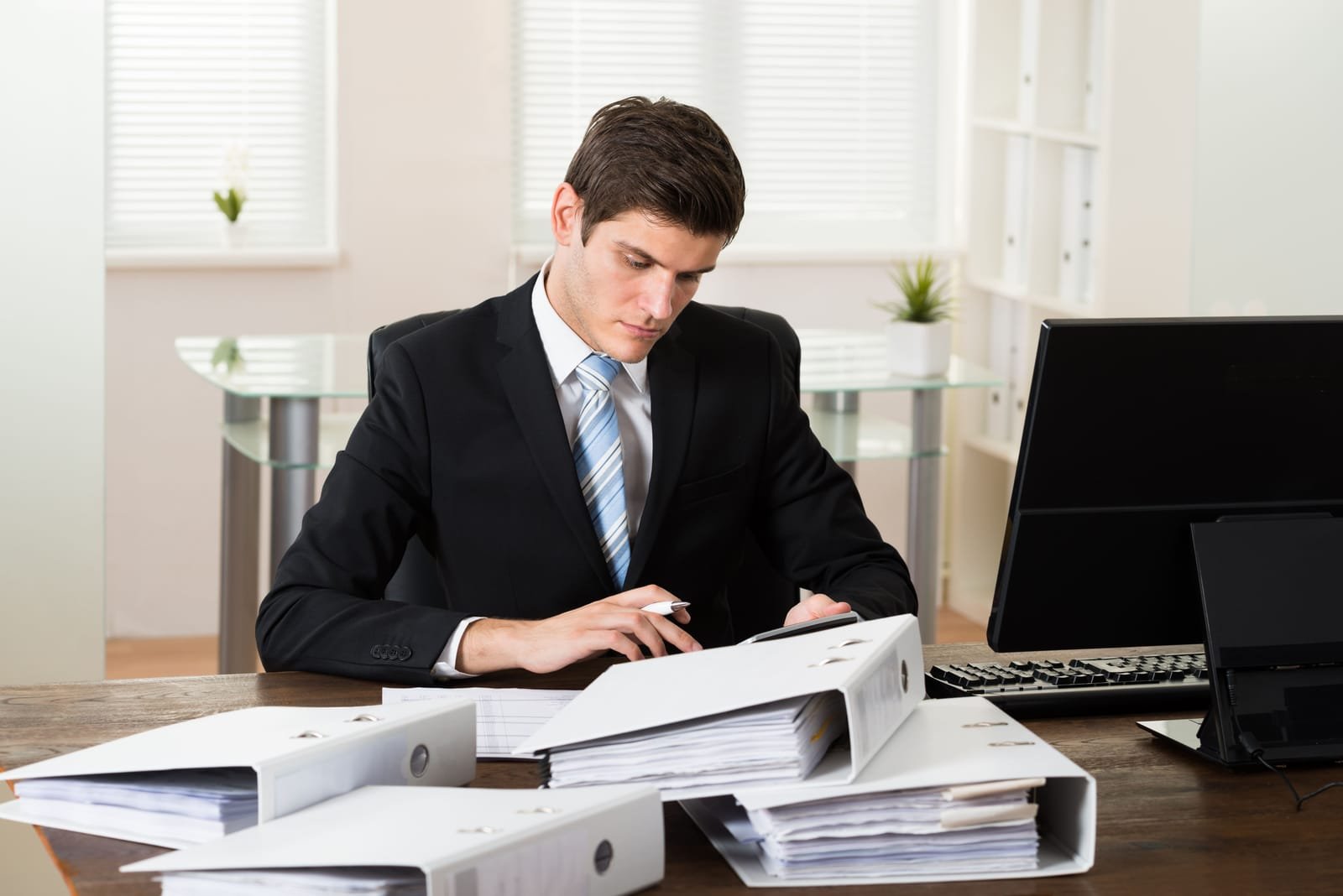 Boekhouder aan zijn bureau met een stapel dossiermappen