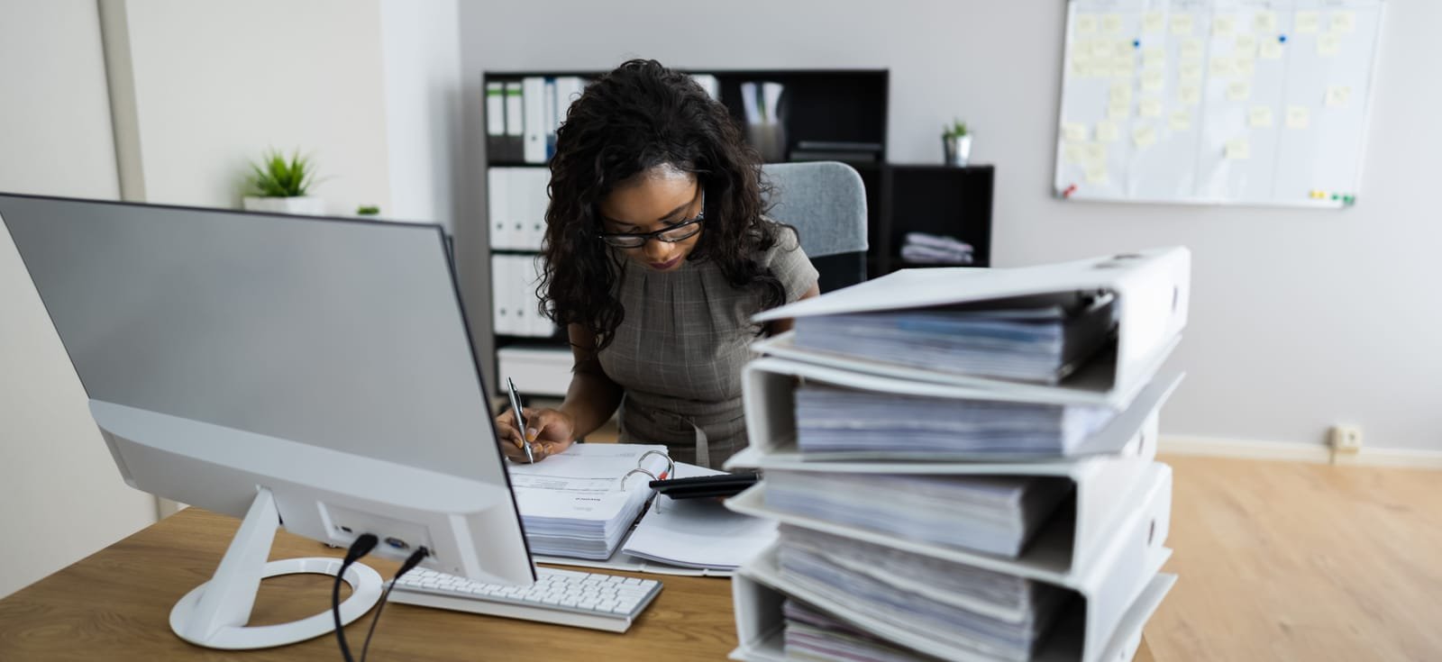Zelfstandige werkt haar administratie bij naast een stapel dossiermappen