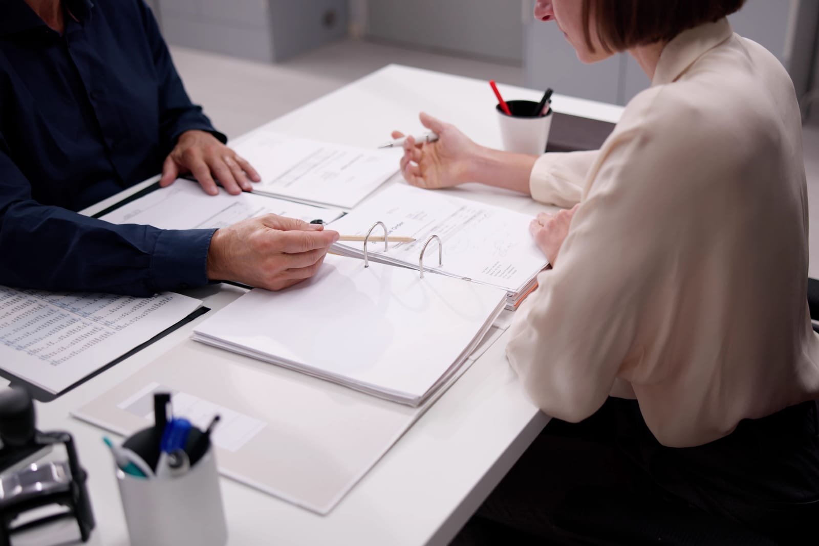 Accountant en klant bekijken samen een dossiermap aan de vergadertafel